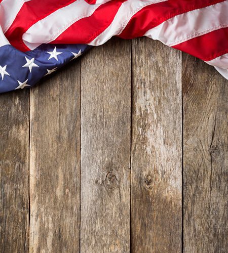 An American Flag Laying on an aged, weathered rustic wooden Background.