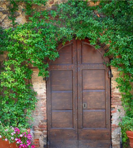 Beautiful old wooden door decorated with flowers from the medieval town, Tuscany, Italy