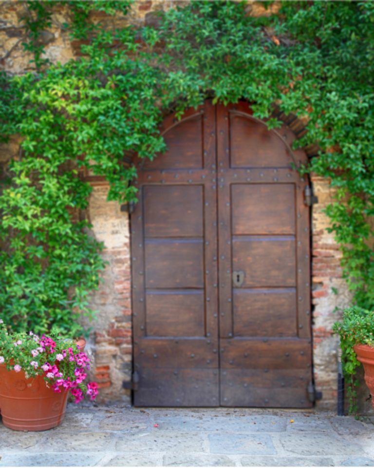 Beautiful old wooden door decorated with flowers from the medieval town, Tuscany, Italy